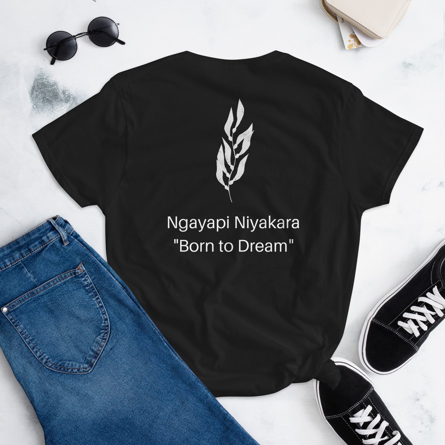 Black Tshirt with ngayapi niyakara - born to dream wording and a kelp frond emblem. Pictured with Denim Jeans and black sneakers.