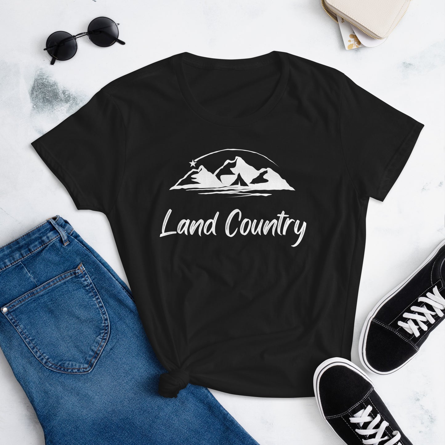 Black tshirt with mountains and the wording Land Country in white on a black tshirt. Paired with Denim Jeans and black sneakers.