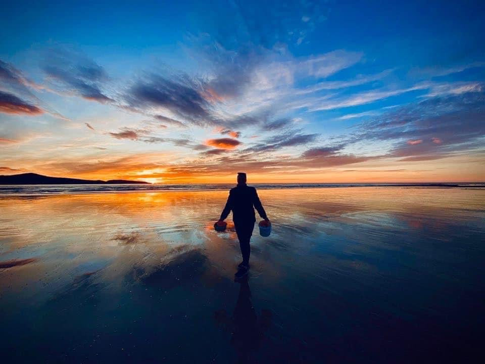 Emma pictured on beach at Sunset. The sky is full of colours in Orange and Blues.